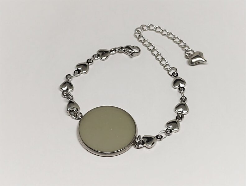 Smalka rokassprādze ar tumsā spīdošu apaļu elementu.